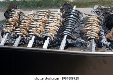 Skewers Of Sardines Over Incandescent And Smoky Embers In Malaga. Typical Food For Holidays And Beach In Spain.