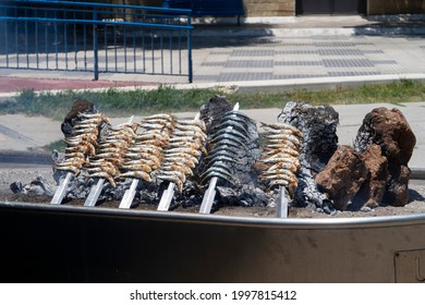 Skewers Of Sardines Over Incandescent And Smoky Embers In Malaga. Typical Food For Holidays And Beach In Spain.