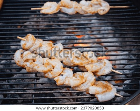 Skewers of shrimp cooking outside on a grill 