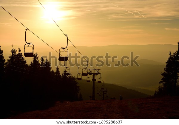 Ski chair lift cable car in the mountains at\
orange sunrise