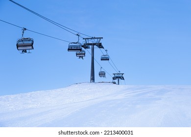 Ski Chair Lift On Top Of Mountain, Ski Slope Prepared For Skiing, Minimal Style Blue Monochrome Winter Scene In  Sheregesh Ski Resort. White Snow, Clear Sky, Cable Road And Small People On Peak