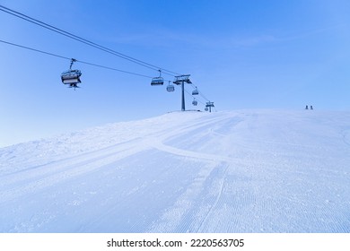 Ski Chair Lift On Top Of Mountain, Ski Slope Prepared For Skiing, Minimal Style Blue Monochrome Winter Scene In  Sheregesh Ski Resort. White Snow, Clear Sky, Cable Road And Small People On Peak