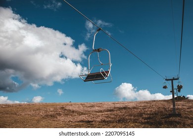 Ski chair-lift in front of the blue sky on a sunny day. No people. Elevator in the autumn season