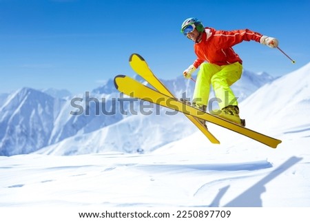 Ski fun. Young man skiing in winter mountains. Extreme sport. Sports competition. Teenager jumping on ski slope. Active colorful sports wear and sage helmet. Outdoor adventure in winter vacation.