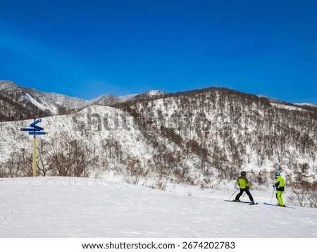 A ski instructor giving a lesson to a student at the slope on a sunny winter day (Togari Onsen, Nagano, Japan)