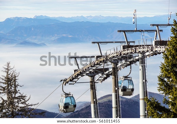 Ski lift cable booth\
or car, Ropeway and cableway transport sistem for skiers with fog\
on valley background
