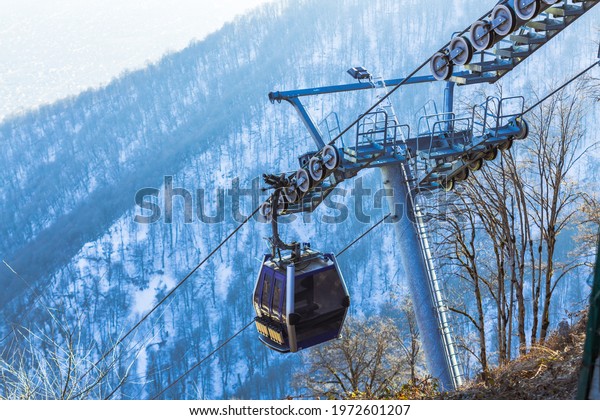 Ski lift cable, Ropeway, and
cableway transport system for skiers with fog on valley
background