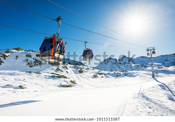 ski lift gondolas against blue\
sky over slope at ski resort on sunny winter day at Italy\
Alps