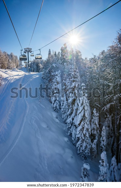 Ski lift in winter\
snowy forest. Sunny day in Krasnaya Polyana ski resort in Caucasus\
mountains, Russia.
