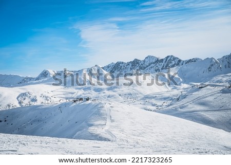 Ski lifts, skiers and snowboarders on pistes in beautiful winter scenery with mountain range in the background, Andorra, El Tarter, Pyrenees Mountains