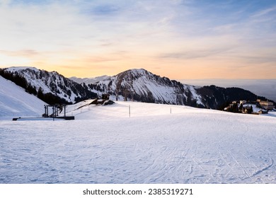 Ski resort and lodges on Klewenalp mountain in Swiss Alps, Switzerland. Popular ski slope and winter sport attraction, winter landscape with snow at sunset.