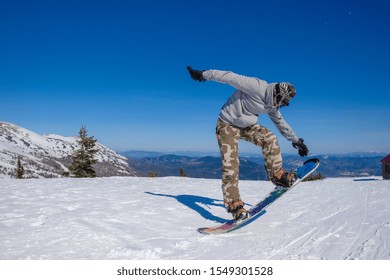 Ski Resort. Snowboarder Jumping On A Snowboard In The Mountain. Long Jump On A Snowboard.