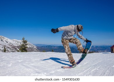 Ski Resort. Snowboarder Jumping On A Snowboard In The Mountain. Long Jump On A Snowboard.