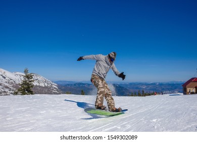 Ski Resort. Snowboarder Jumping On A Snowboard In The Mountain. Long Jump On A Snowboard.