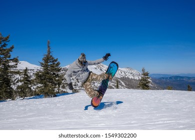 Ski Resort. Snowboarder Jumping On A Snowboard In The Mountain. Long Jump On A Snowboard.