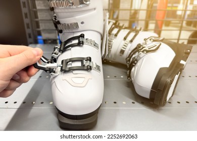 Ski shoe store. White ski boots lie on a shelf in the store. A man's hand checks the fastener lock on a specialized ski shoe. The concept of winter sports and ski holidays