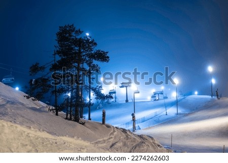 A ski slope in Finland illuminated by lanterns at night. Ski resort. Ski lift.
