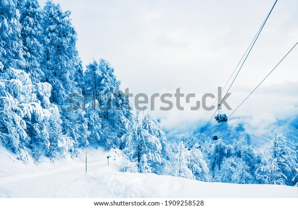 Ski slope and gondola lift in winter ski\
resort. Rosa Khutor, Sochi, Russia. Beautiful snow-covered\
mountains and forest, winter\
landscape