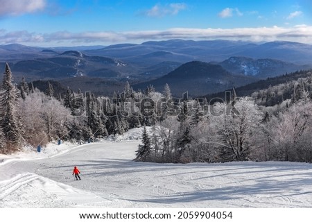 Ski slope mountain scenery lansdcape with lonelys skier skiing downhill on first tracks fresh snow alone with frozen treeline. Winter sport resort, people skiing at Mont-Tremblant, Quebec, Canada.