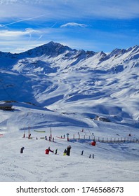 Ski slopes with skiers, blue sky and mountains