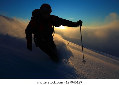 Ski tourer descending on skies at sunset, Tarcu mountains, Romania