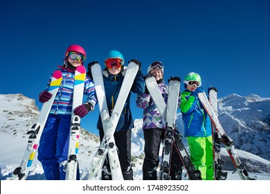 Ski vacation portrait many children stand with sport equipment in hands lean to camera wearing color google and helmets