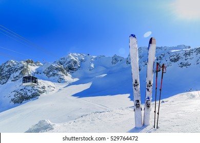 Ski winter season - mountains, cable car and ski equipments on ski run, cable car ski lift in background.