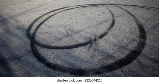 skid marks on a road surface. Circular tire marks left by drivers doing doughnuts - Shutterstock ID 2226344215