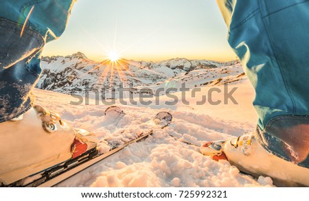 Skier athlete standing in front of wonderful sunset in ski resort - Winter extreme sport concept with person on top of the mountain ready to ride down - Focus on intersection skis