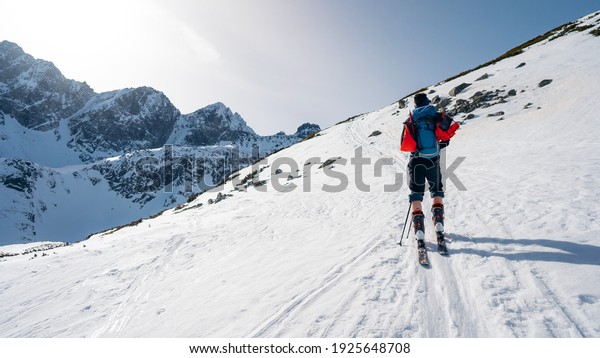 A skier is climbing the hill using skitour\
equipment. Ski Touring in mountains. Man walking in a winter\
landscape. Adventure outdoor\
activity