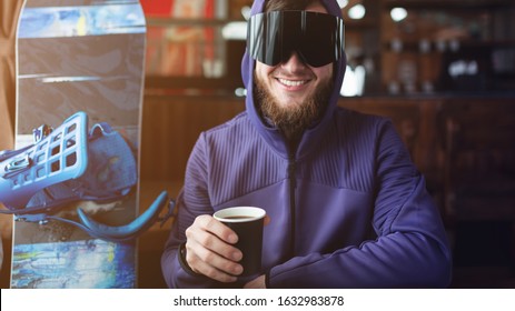 Skier Drinking Hot Coffee From Paper Cup In Ski Lodge Bar Portrait. Snowboarding Background.