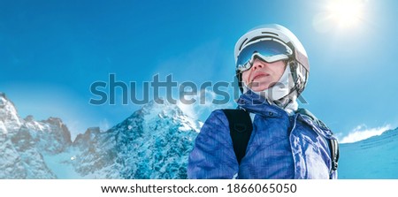 Skier female portrait in safe ski helmet and goggles with picturesque snowy Tatry mountains background. Active people winer vacation concept image.