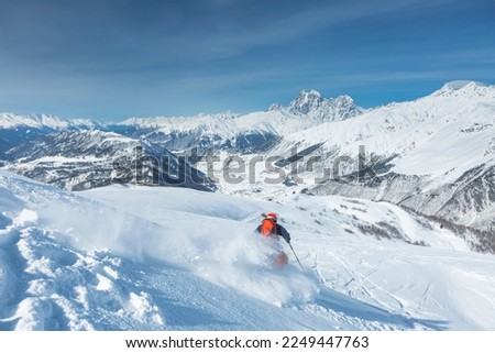 A skier is freeriding against the background of the peaks of Mount Ushba, the Great Caucasian Range in winter,