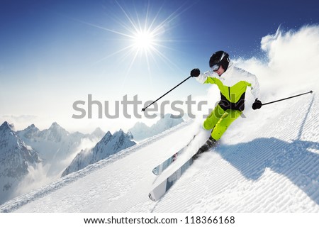 Skier in mountains, prepared piste and sunny day