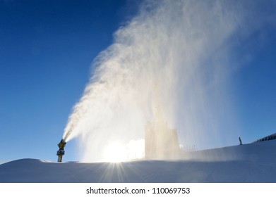 skier near a snow cannon which is making powder snow