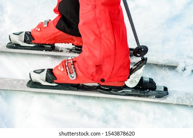 Skier In Red Ski Suit And Red Ski Boots And White Skis, Closeup.