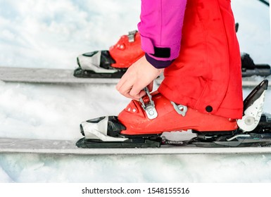 Skier In Red Ski Suit And Red Ski Boots And White Skis, Closeup.