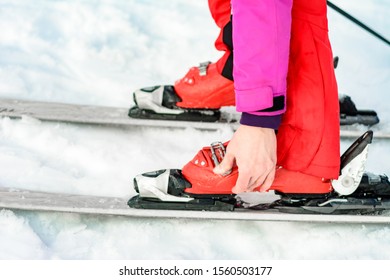 Skier In Red Ski Suit And Red Ski Boots And White Skis, Closeup.