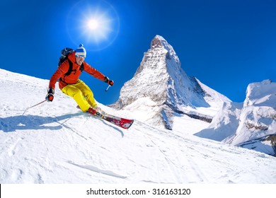 Skier Skiing Downhill Against Matterhorn Peak In  Switzerland