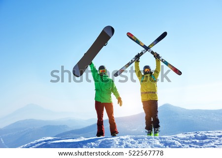 Skier and snowboarder stands mountain top with ski and snowboard in hands. Skiing and snowboarding concept. Sheregesh ski resort