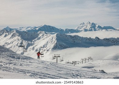 A skier stands near the Cascade chairlift, surrounded by breathtaking snow-covered peaks in Val d'Isère, France