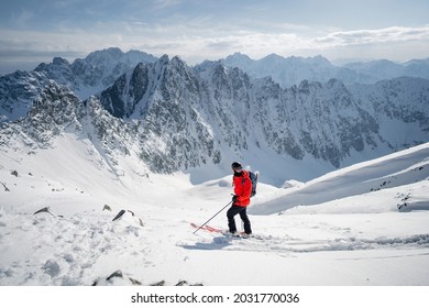 A skier is walking up the hill. Skitouring in Alps. Sunny weather. Hiking, adventure tourism, travel. Mountaineer backcountry ski walking in the mountains.