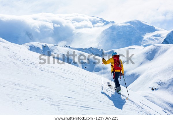 A skier is walking up the hill. Skitouring in\
Alps. Sunny weather.
