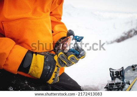 A skier wearing gloves switches ski bindings from ski touring mode to normal skiing mode. Close-up skitour preparation concept