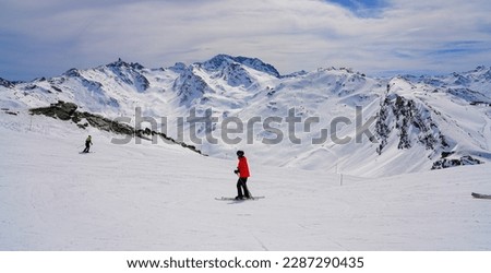 Skier wearing a red jacket and a helmet on a piste passing in front of the Mont de la Chambre (