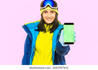 Skier young woman wear padded windbreaker jacket hat ski goggles mask use point green screen mobile cell phone travel rest spend weekend winter season in mountains isolated on plain blue background - Powered by Shutterstock