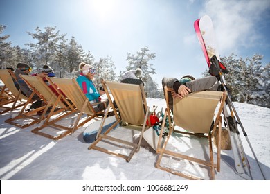 Skiers Enjoys In Sunbed After Skiing On Ski Terrain, Back View