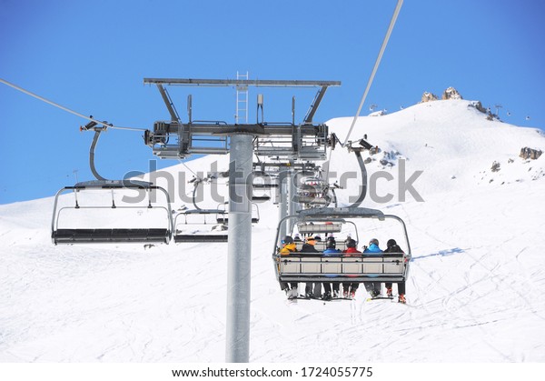 Skiers  going up on the hill with\
chairlift  in Courchevel ski valley, Rhône-Alpes, France.\
