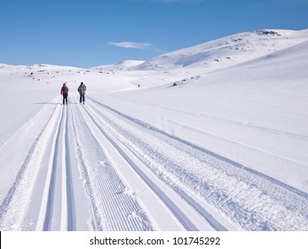 Skiers in norwegian mountain in well prepared ski tracks at easter