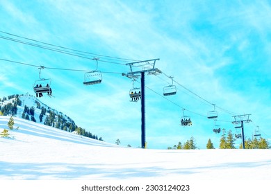 Skiers riding a chairlift on a sunny winter day at Mammoth Ski Resort.